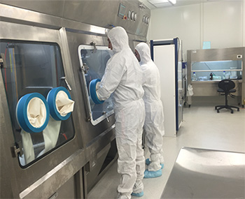 2 people wearing full body overalls whilst working in a laboratory. 2 people wearing full body overalls whilst working in a laboratory.