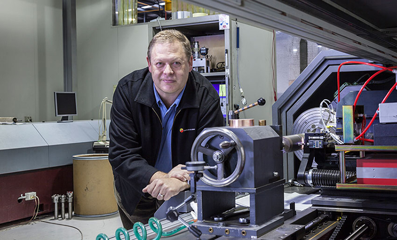 Person leaning on a lathe in a workshop. Person leaning on a lathe in a workshop.