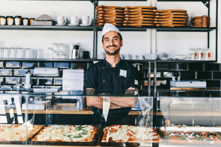 A man stands behind a counter with food in his restaurant