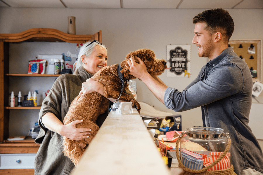 A dog groomer talks to a customer with her dog