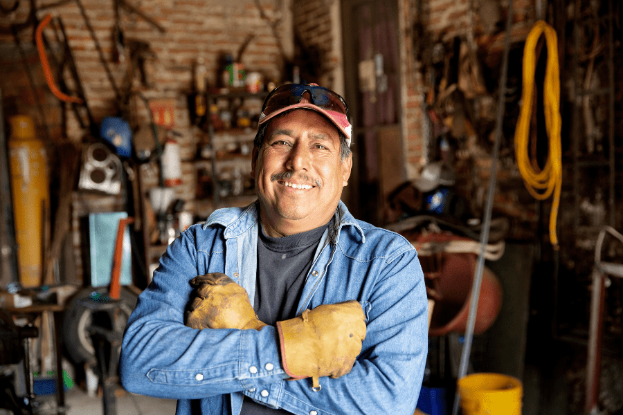 Smiling man wearing work gloves standing in a shed